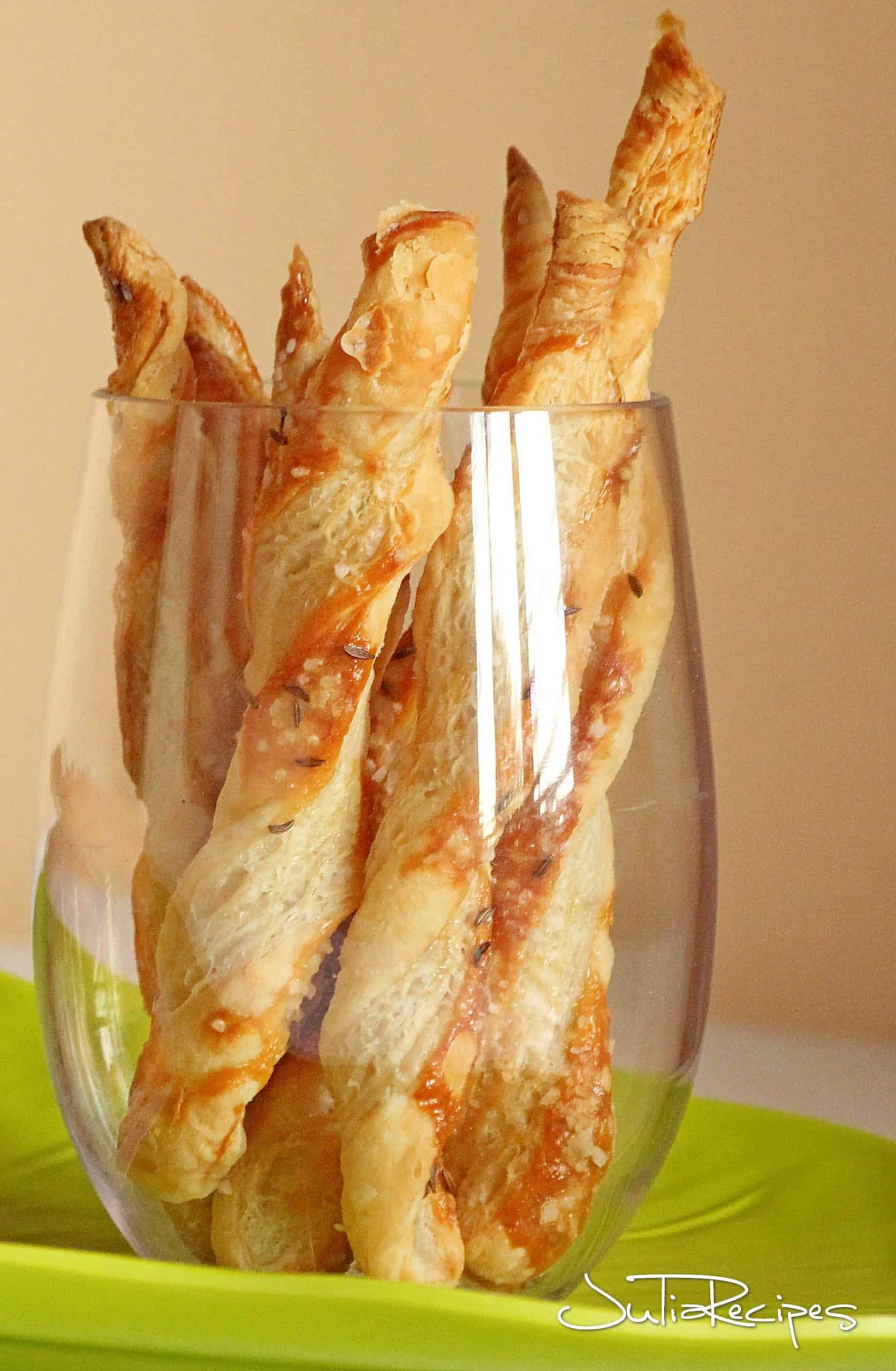 puff pastry sticks with parmesan in wine glass on green platter