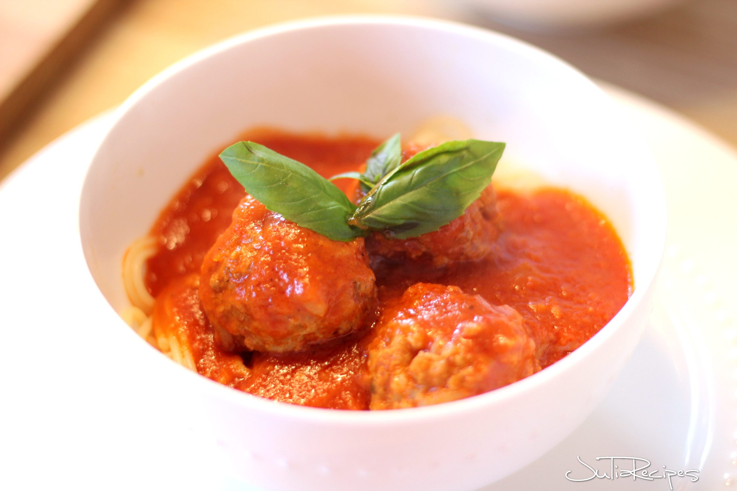 delicious meatballs with tomato sauce and spaghetti in white bowl