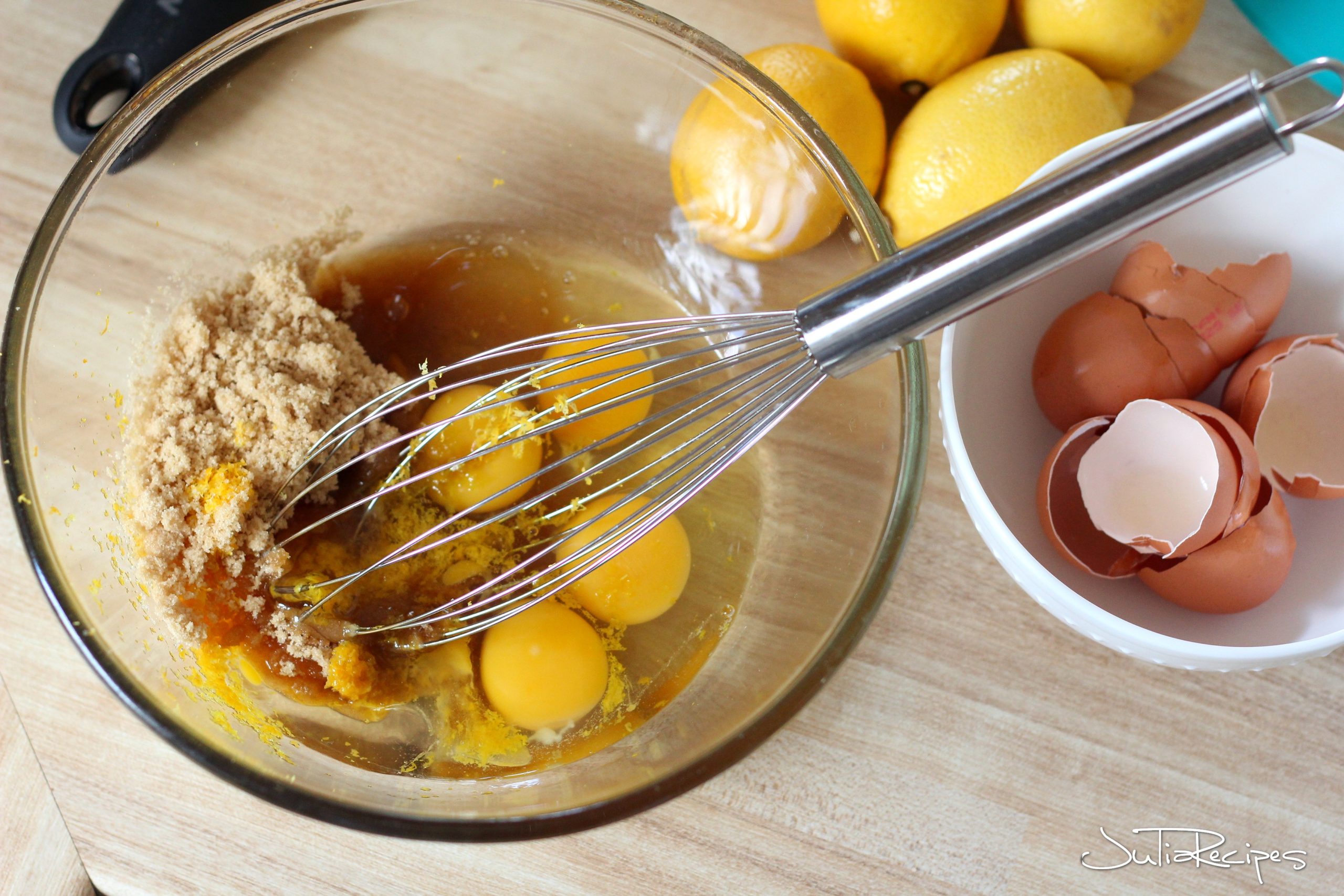 mixing ingredeints for mini lemon tarts- eggs with sugar and vanilla in transparent bowl
