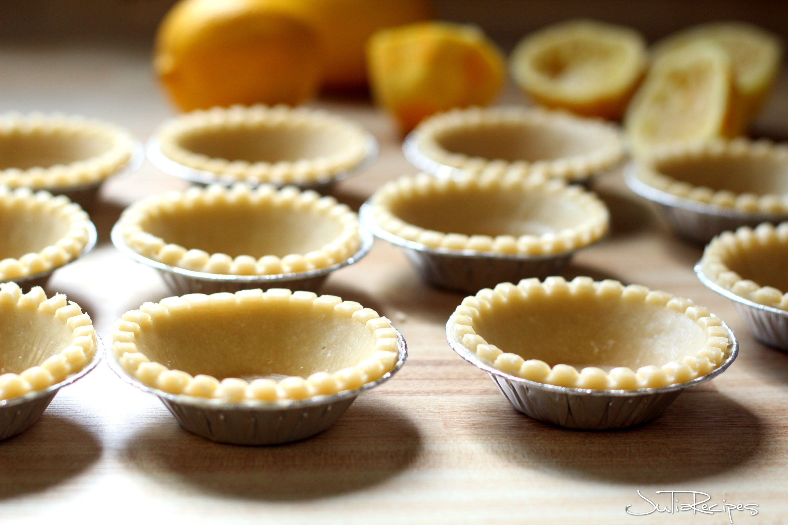 pre-made tart shells on counter with lemons in the background