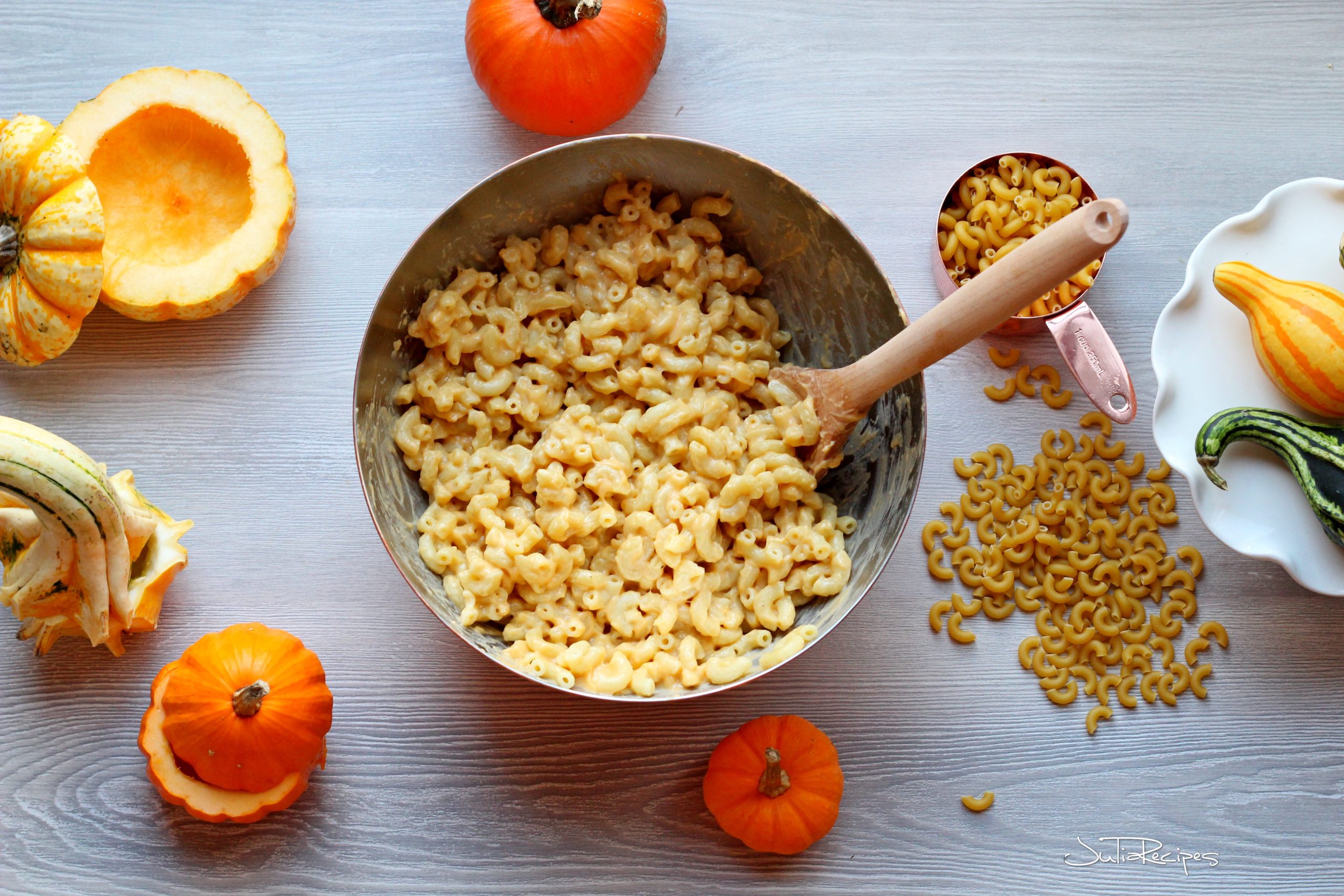 Macaroni and cheese with pumpkin puree mixed together in bowl