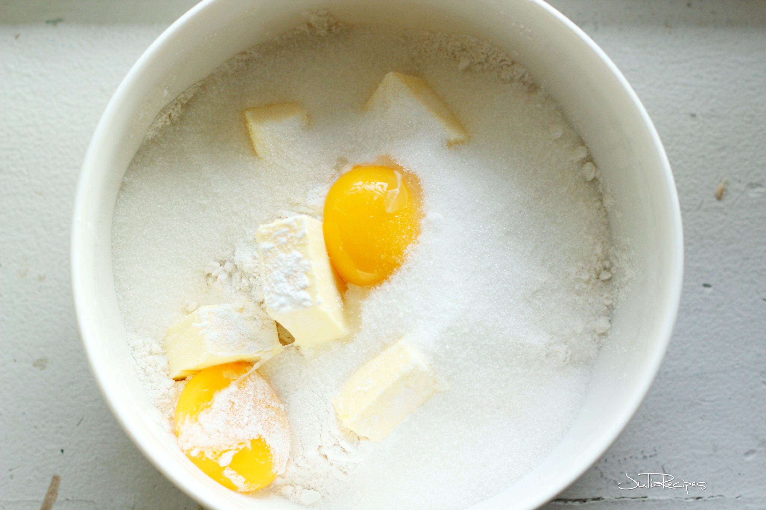 mixing flour with butter and eggs in white bowl