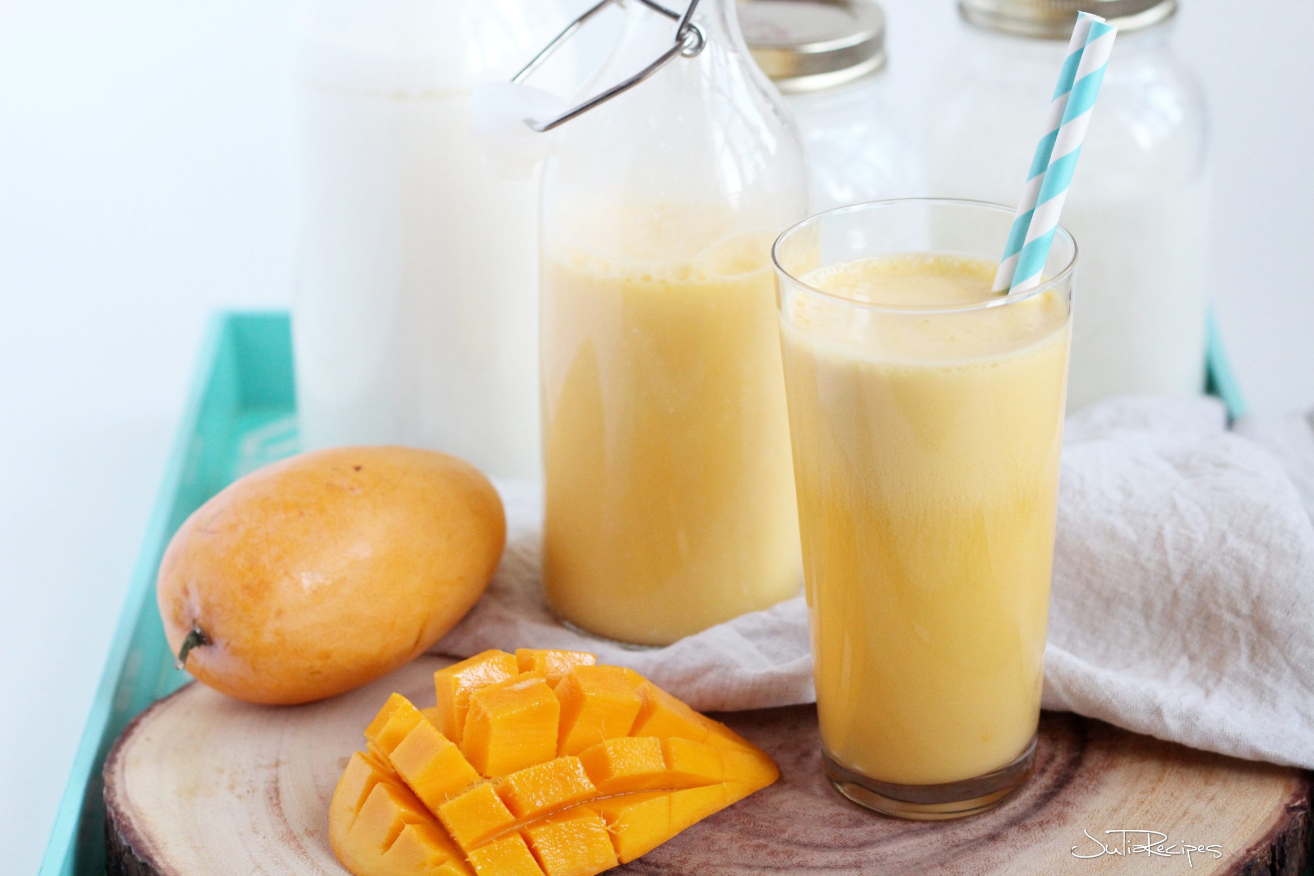 Mango homemade kefir on wooden board with mango fruit cut on the side
