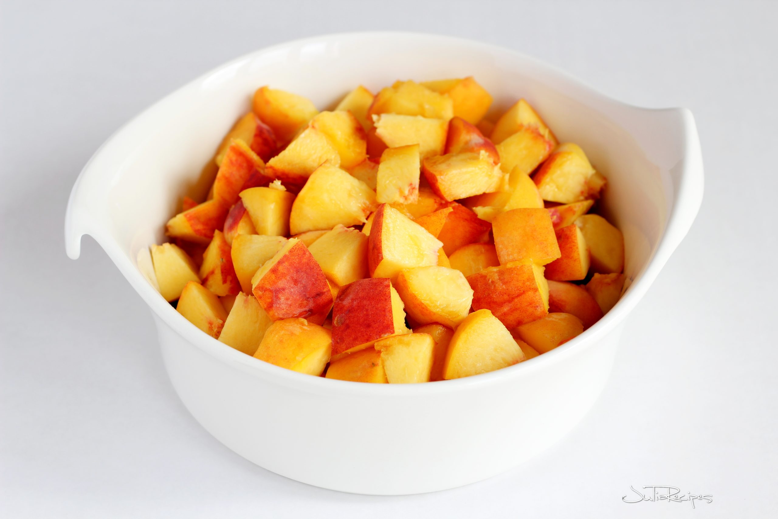 cubed peaches in white bowl