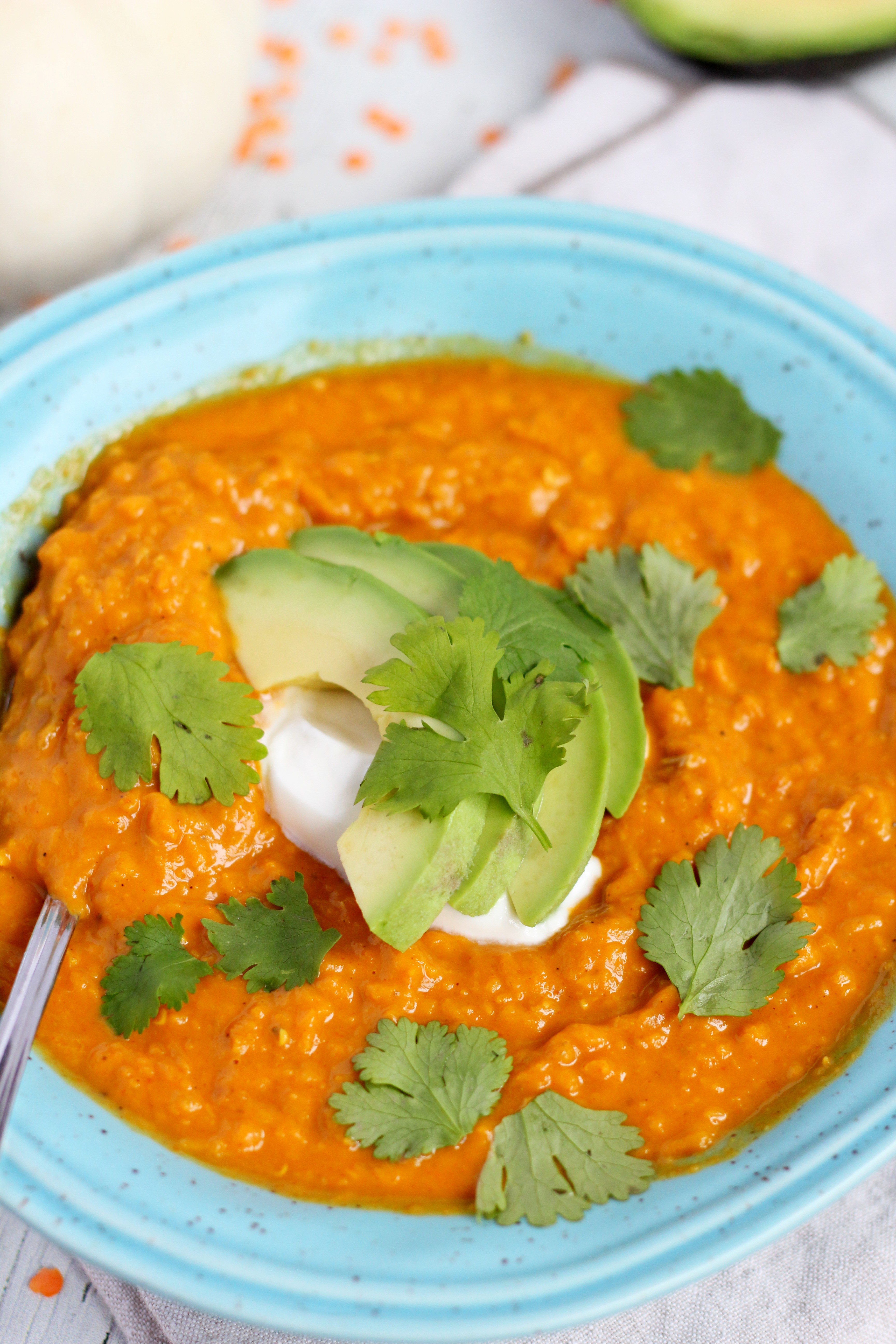 lentil sauce with avocado and sour cream in blue plate