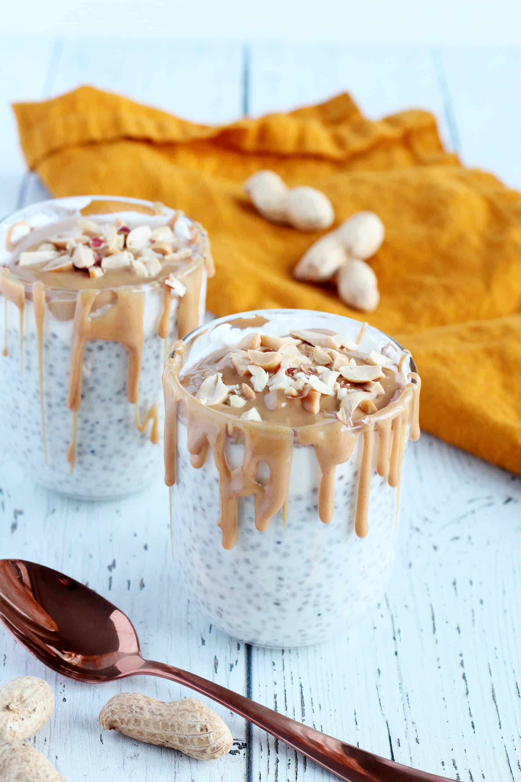 two glasses with chia seed pudding topped with peanut butter and peanuts