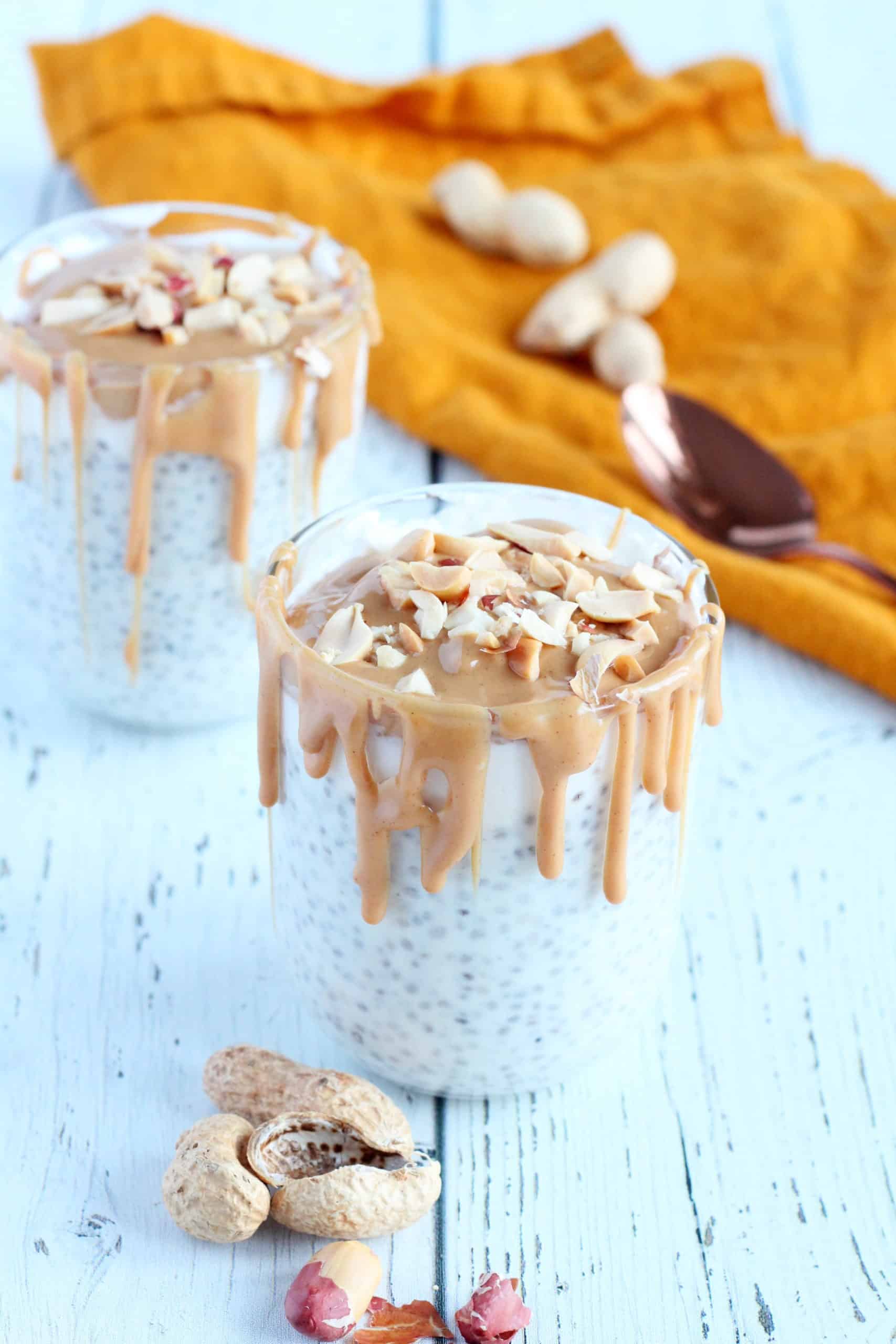 peanut butter chia pudding in two glasses with yellow napkin and spoon
