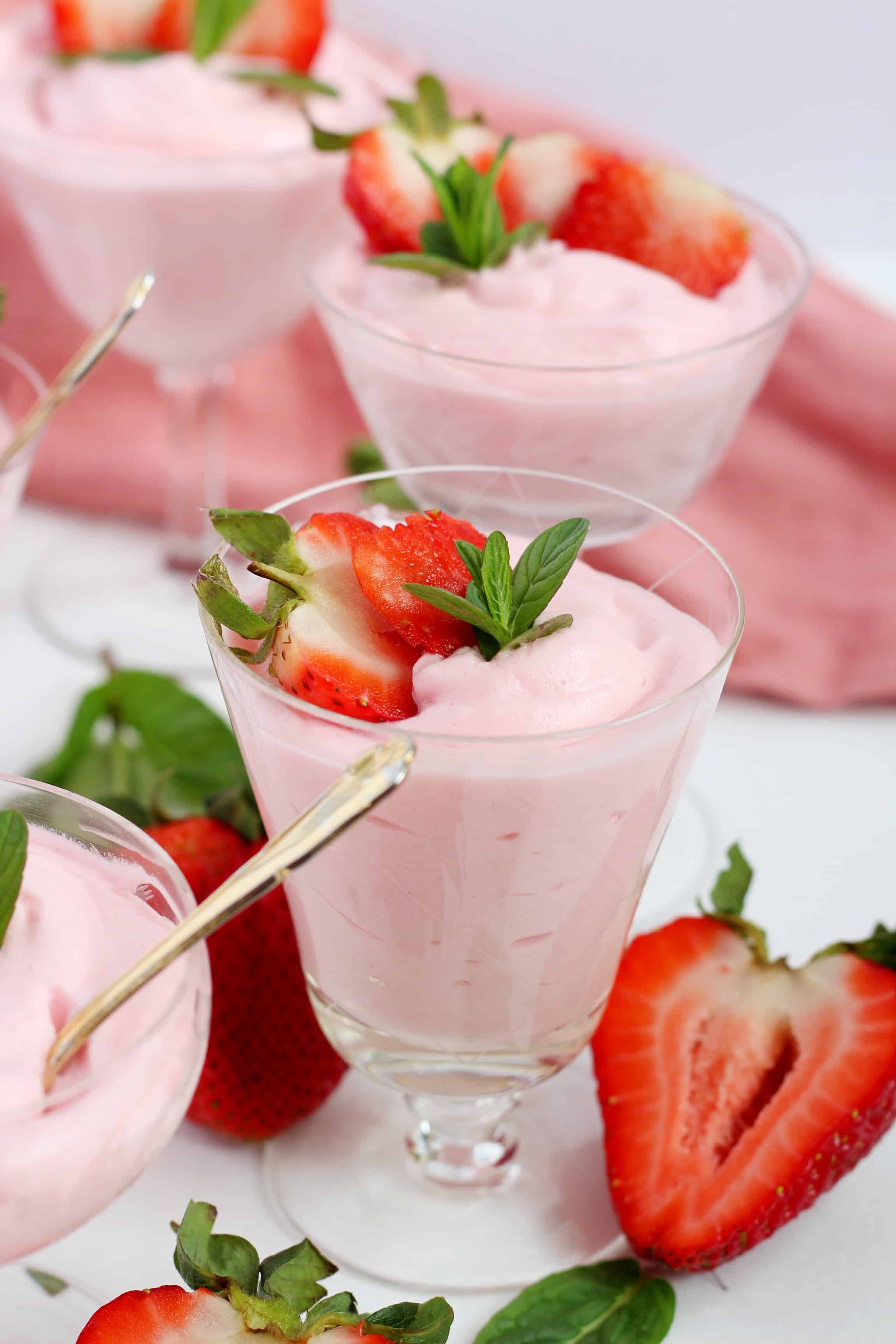 strawberry mousse in cocktail glasses garnished with strawberries and mint leaves