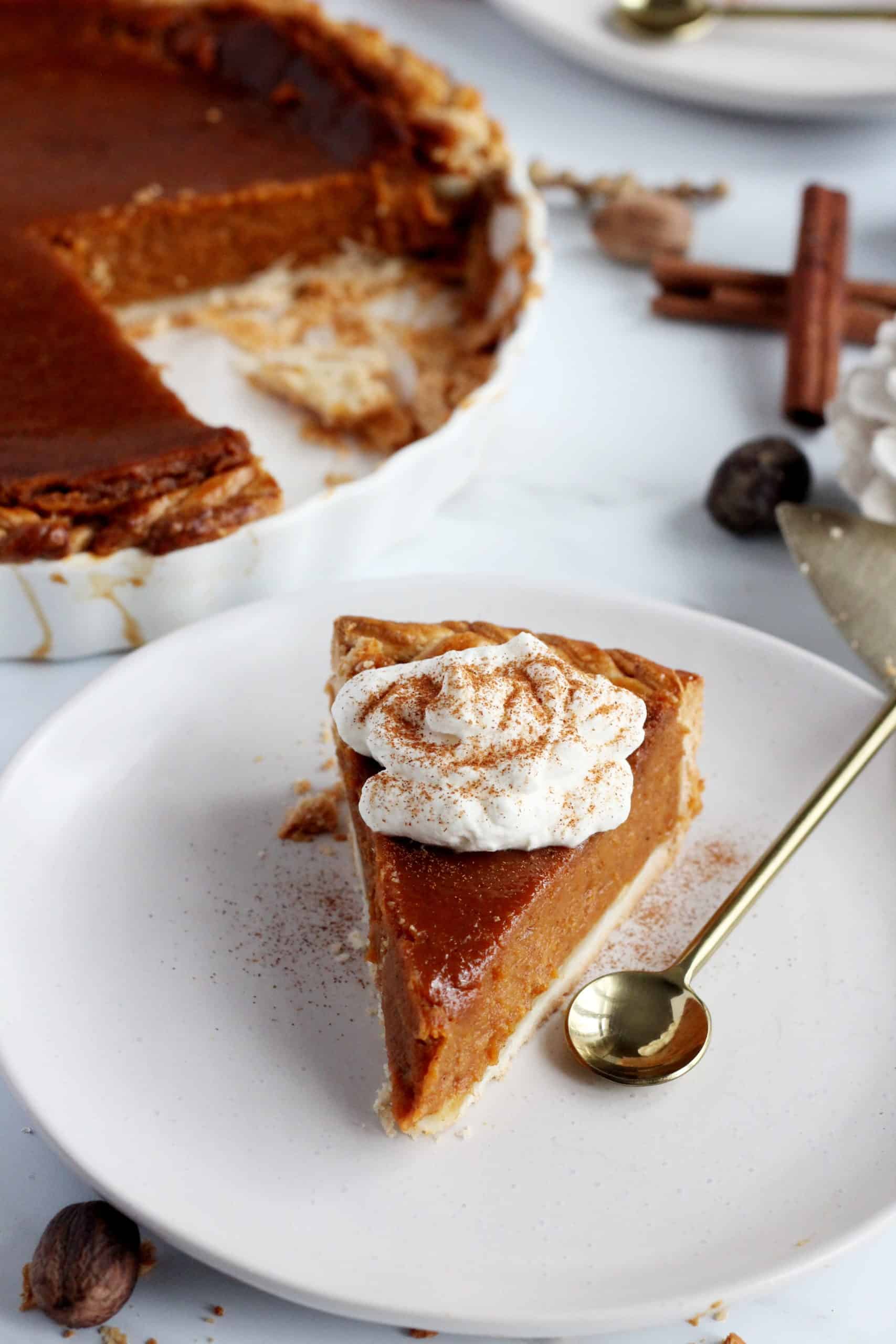 pumpkin pie with whipped cream on top dollop on top served on white plate