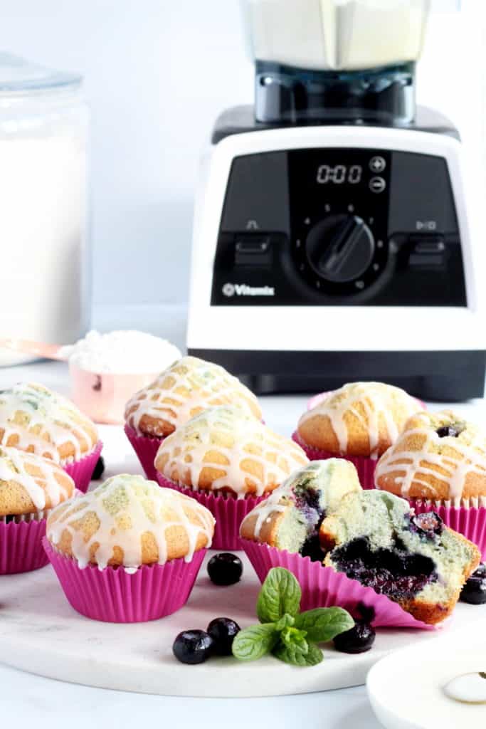 Many bluberry muffins laying on marble board with Vitamix blender