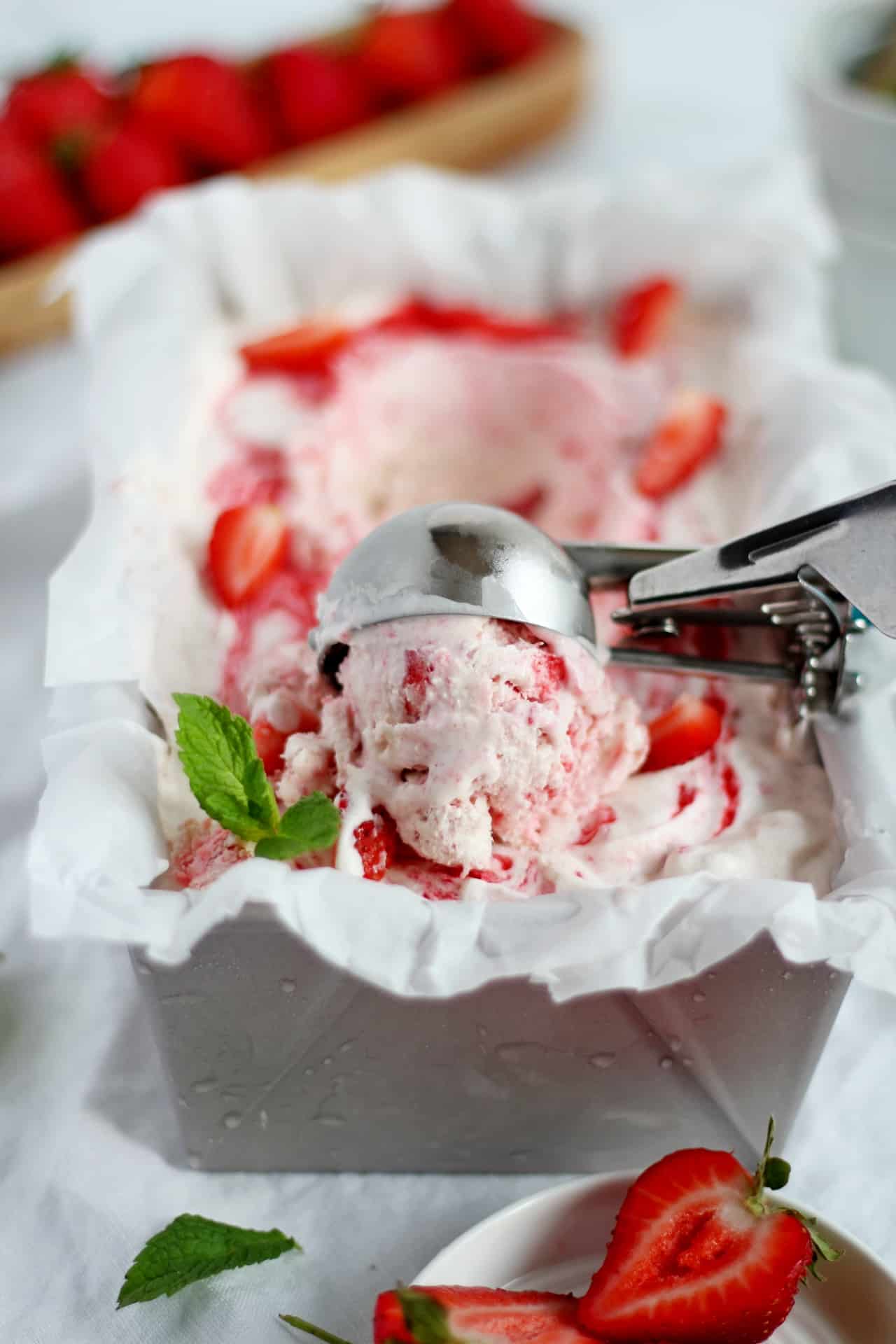 scooping strawberry ice cream from loaf pan