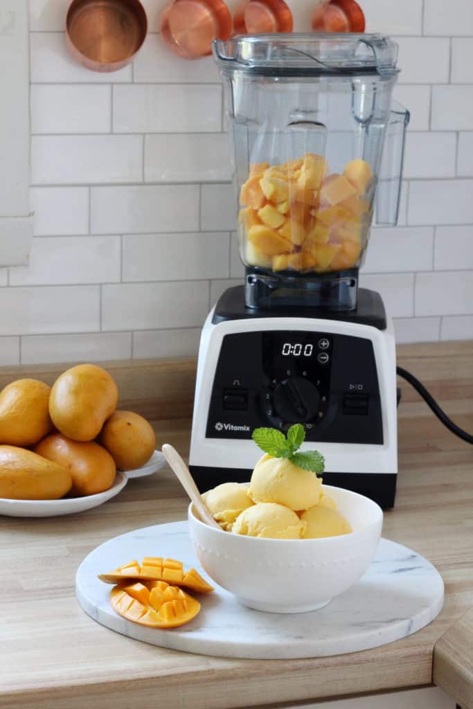 mango sherbet scooped in white bowl with vitamix blender in the background
