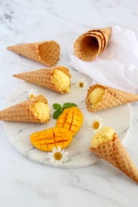 mango sherbet in waffle cones on marble stand