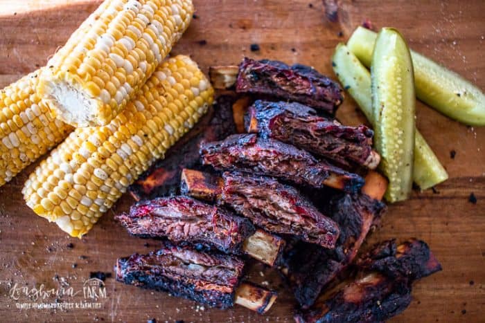 Smoked Beef Ribs with corn and pickels on wooden board