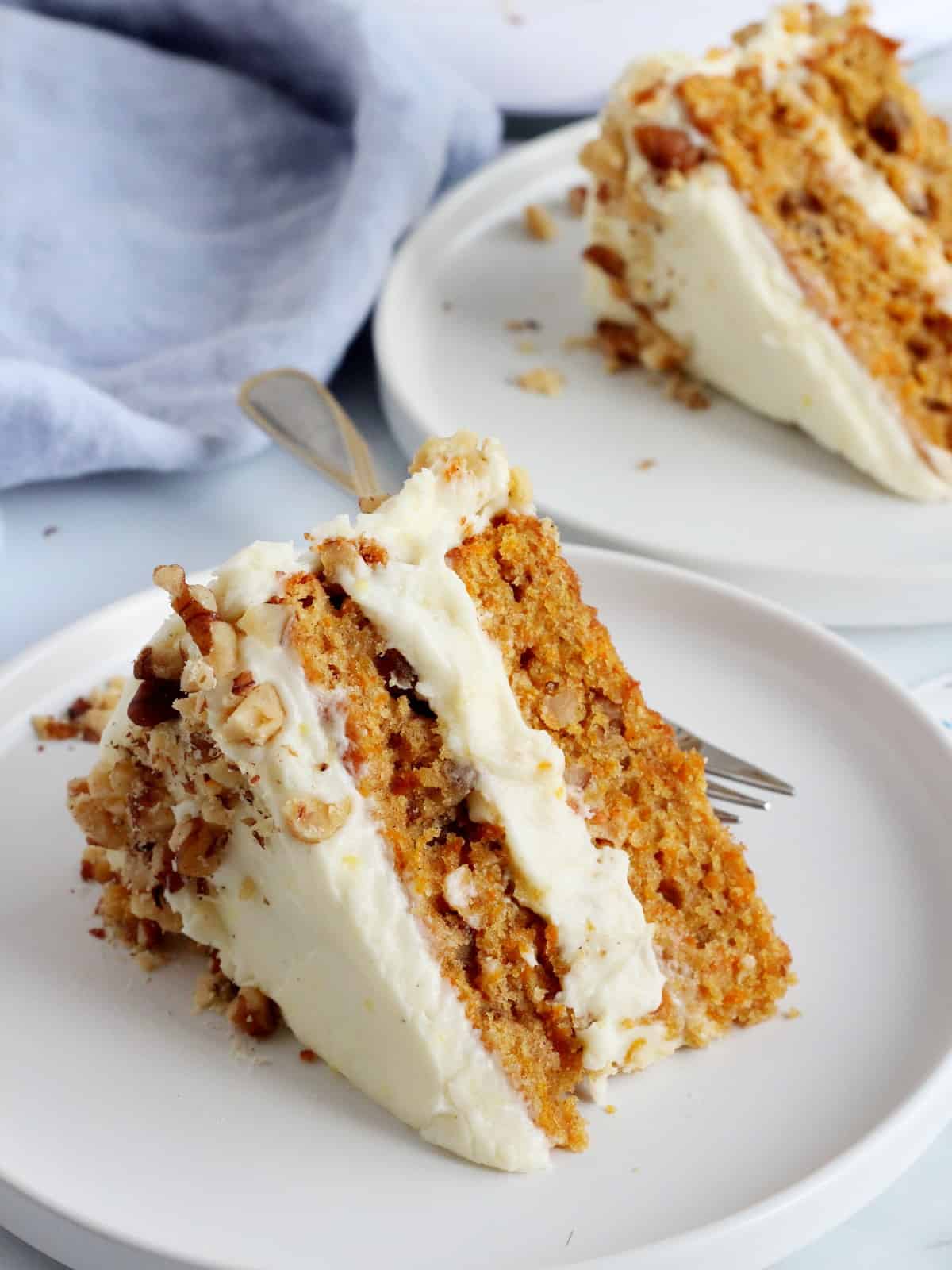 two slices of carrot cake on white plates