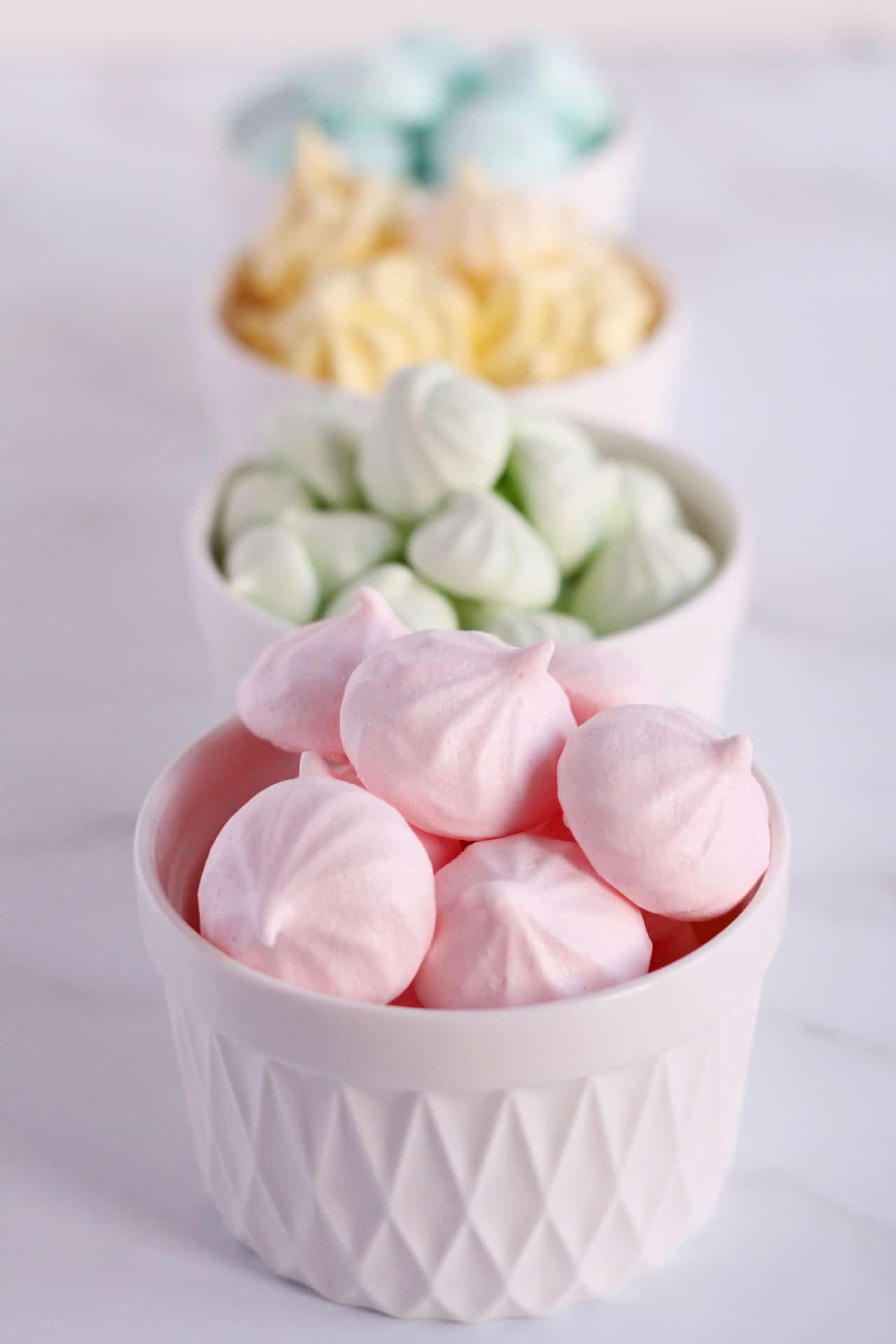 kiss meringues in four different colors pink,green, yellow and bllue. each in different container