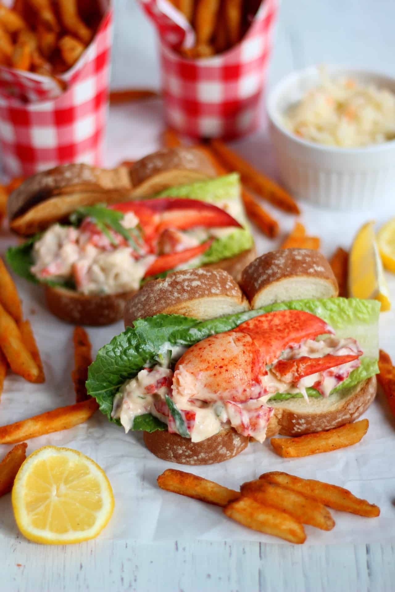 filled hot dog buns with lobster mixture and salad. Sweet potato french fries laying around.