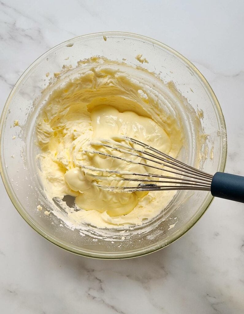 Add melted white chocolate to creamed butter and sugar.