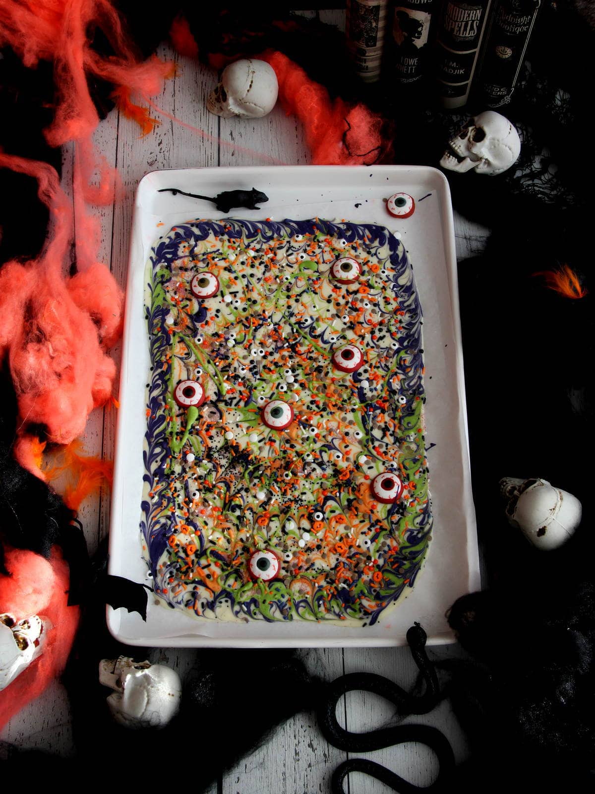 Halloween bark made from white chocolate placed on white baking sheet