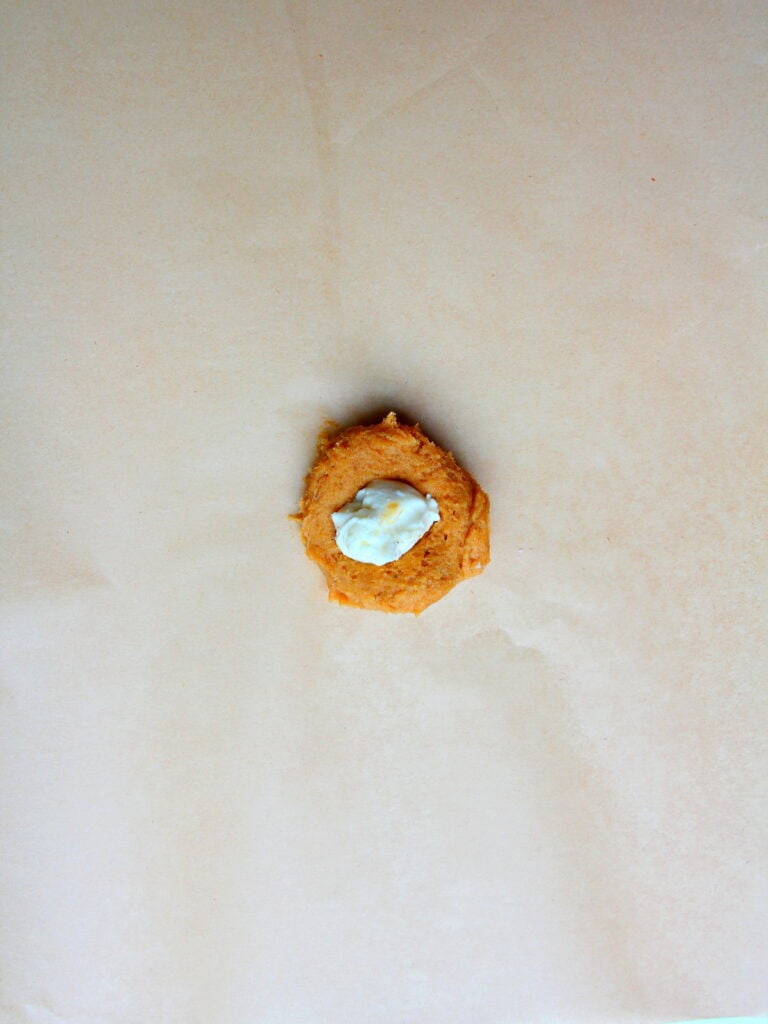 pumpkin cookie on brown parchment paper filled with cheesecake filling