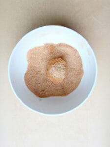 cinnamon sugar in white bowl with raw pumpkin cookie dough