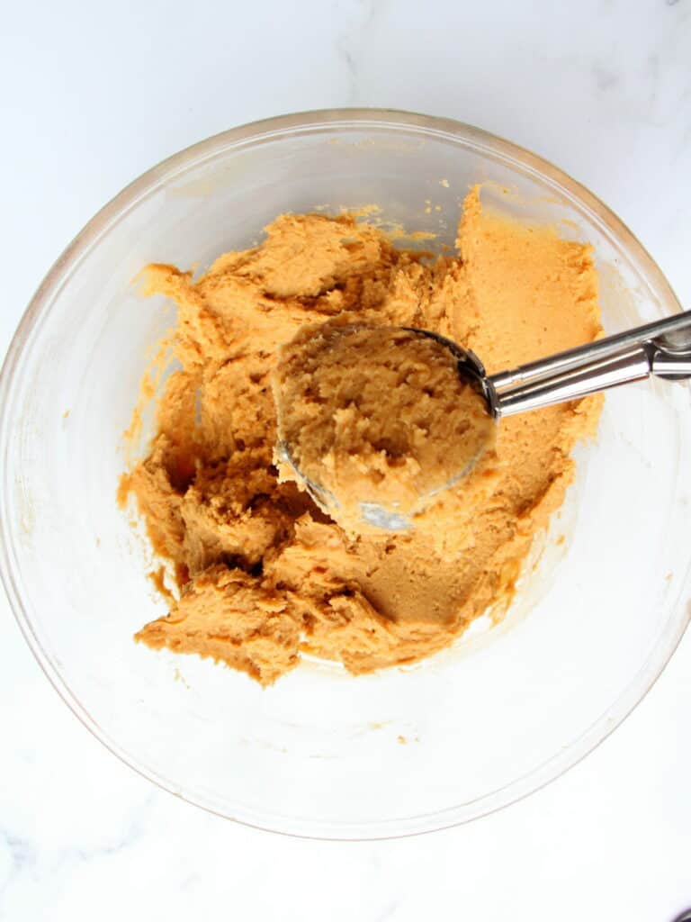 pumpkin cookie dough in transparent bowl scooped with ice cream scooper