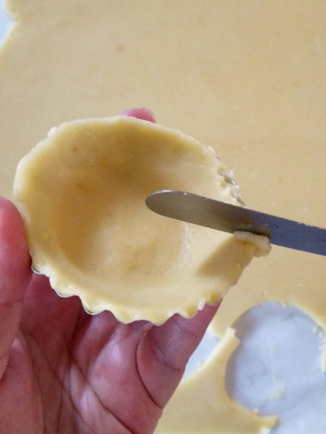 uniforming the dough in mini tart shell