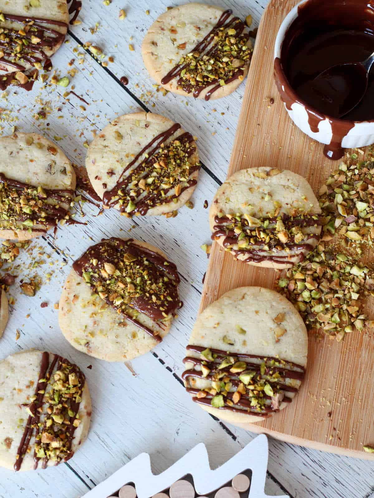Shrortbread  cookies with pistachios on white background with melted chocolate in white bowl