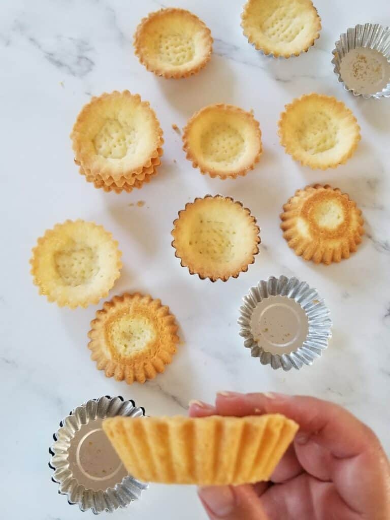 close up on baked mini tarts scattered on marble background