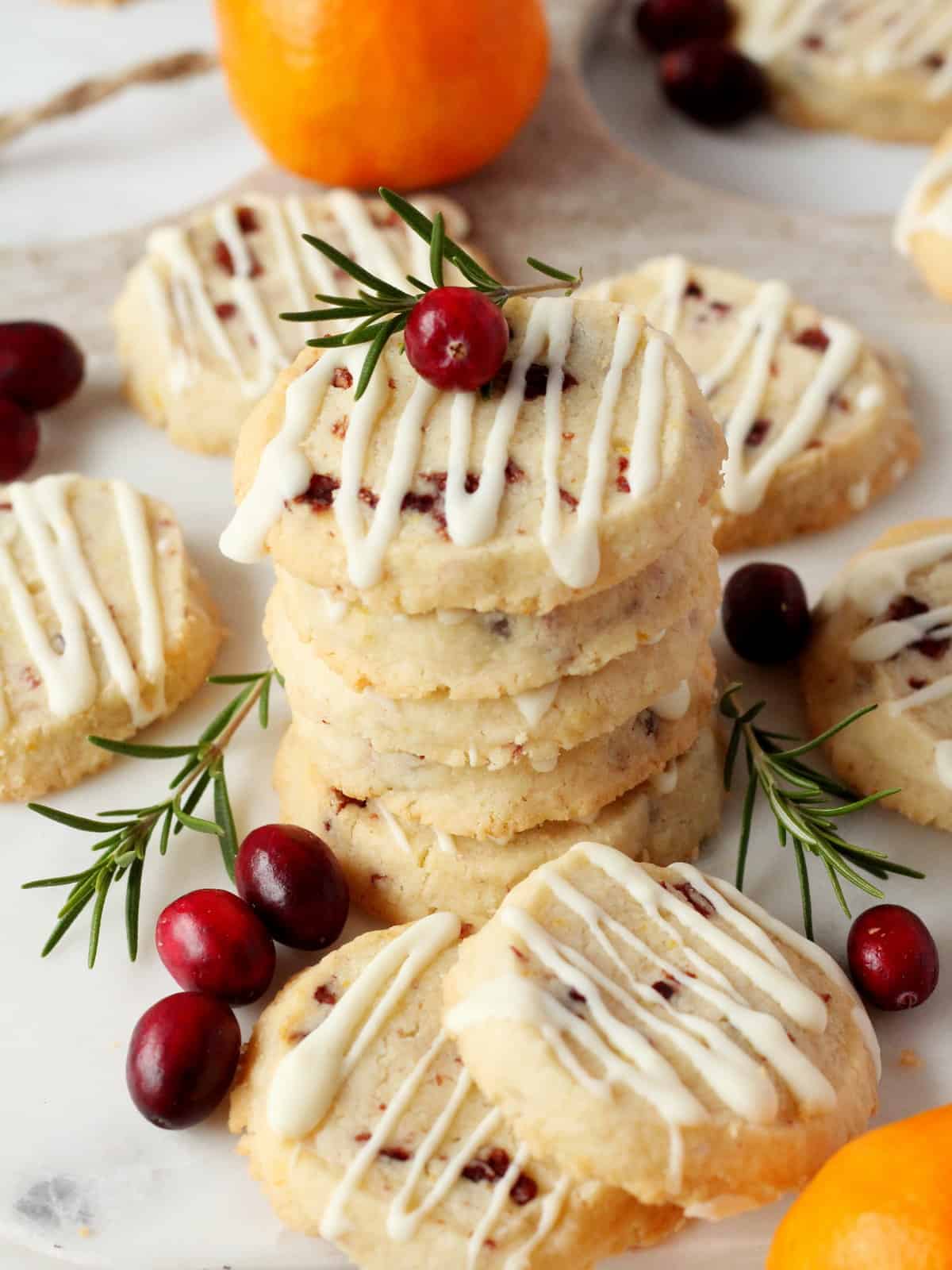 orange zest and cranberry cookies on white marble board, decorated with fresh cranberries, oranges and rosemary branch