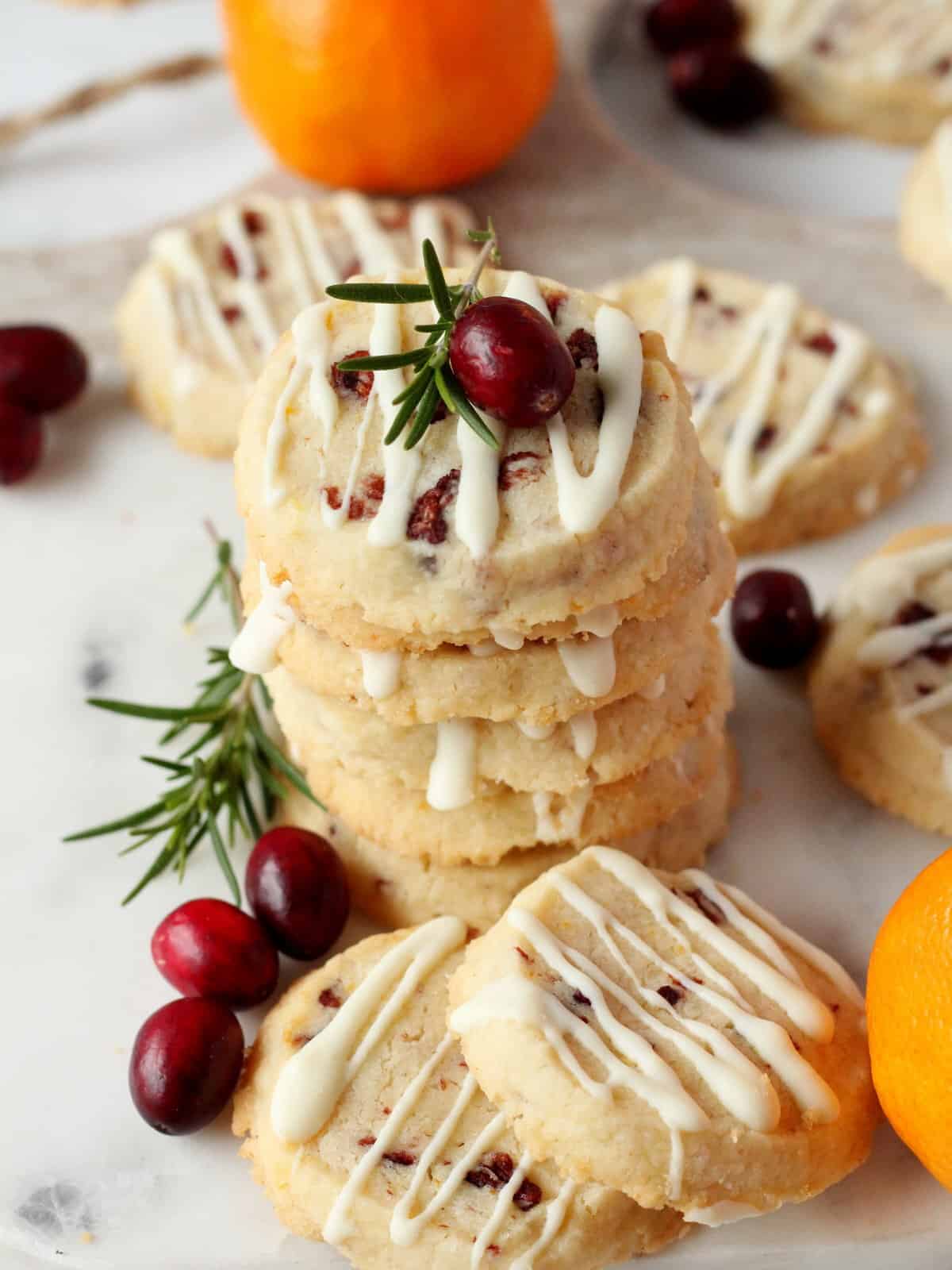 orange zest and cranberry cookies on white marble board, decorated with fresh cranberries, oranges and rosemary branch