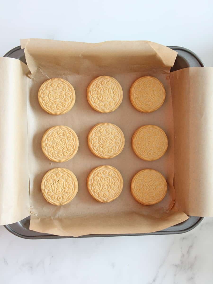 Baking pan with parchment paper and nine Oreo cookies place carefully inside the pan