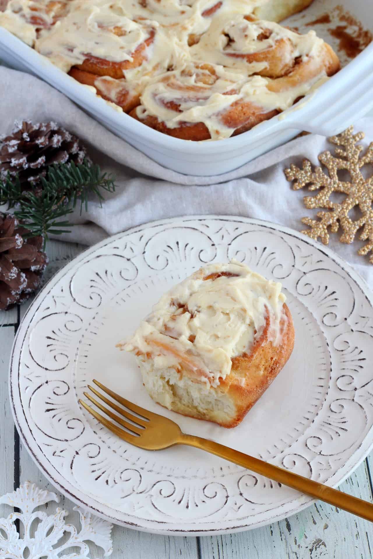 eggnog cinnamon roll on white plate with golden fork