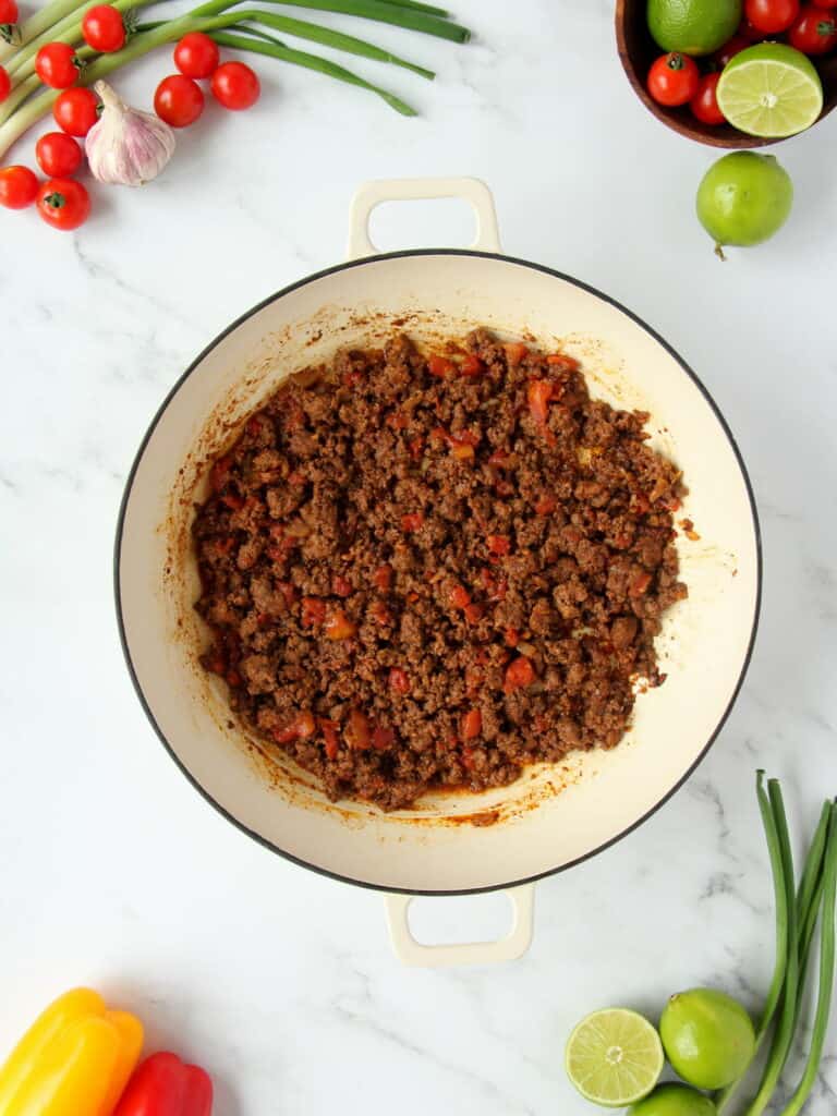 cooking the beef with taco seasoning in white skillet