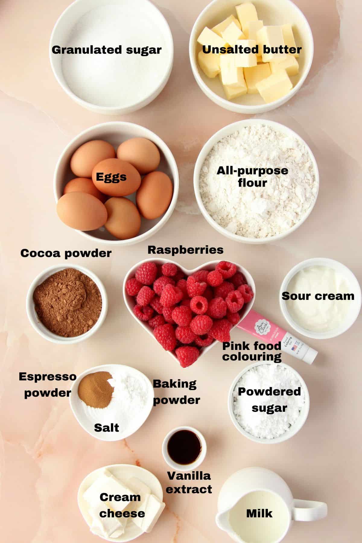 Ingredients for chocolate pound cake with hidden heart laid on pink marble background