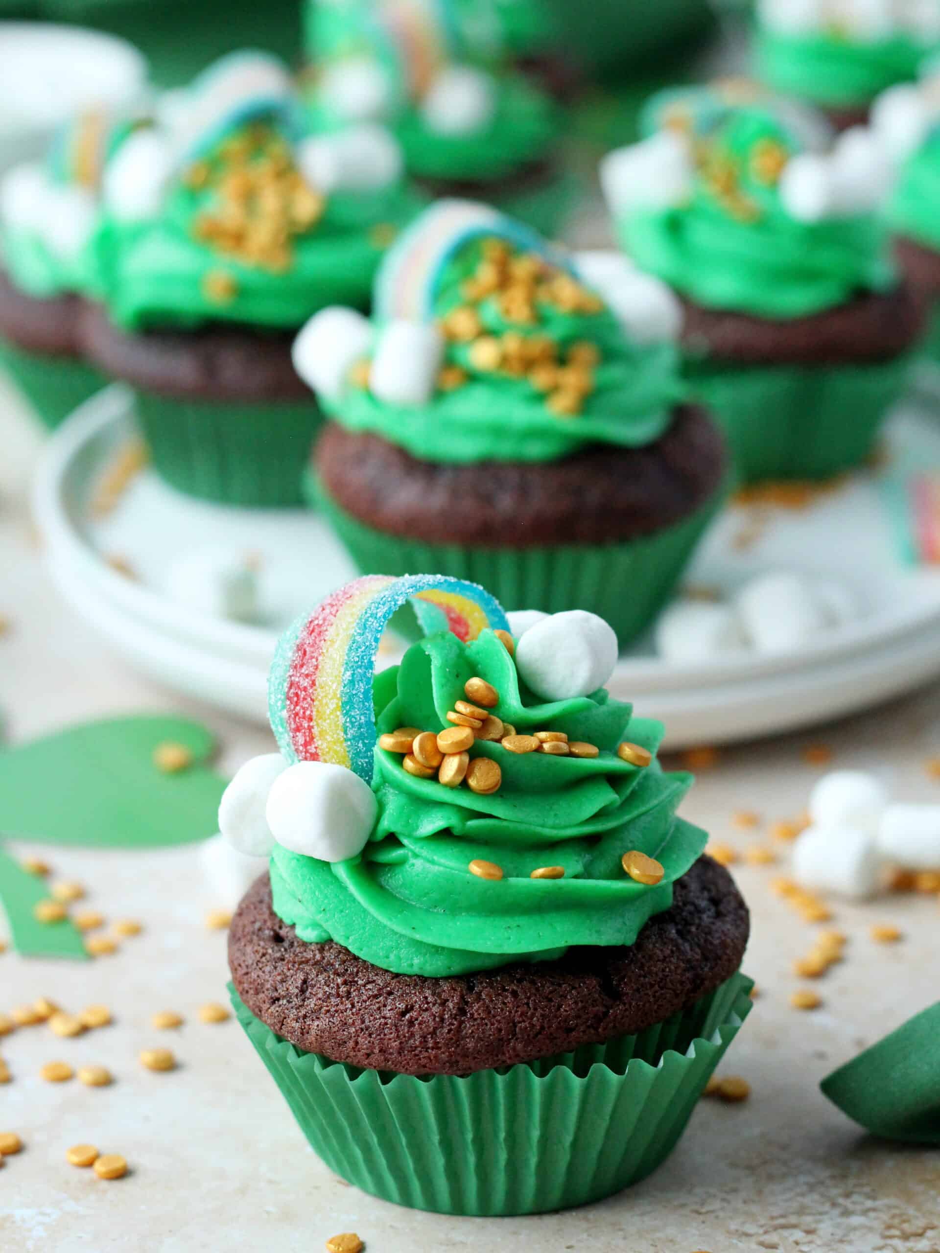 st patrick's day cupcakes with green buttercream, topped with rainbow candy and small marshmallow clouds