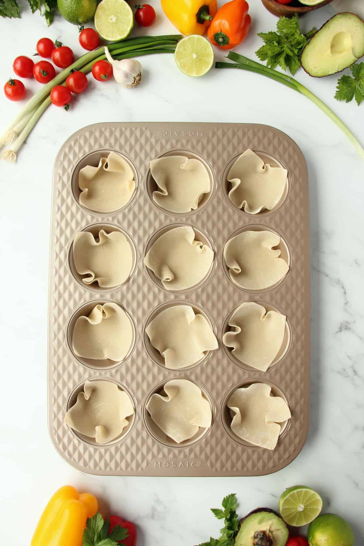 placing wonton wrappers inside the muffin pan