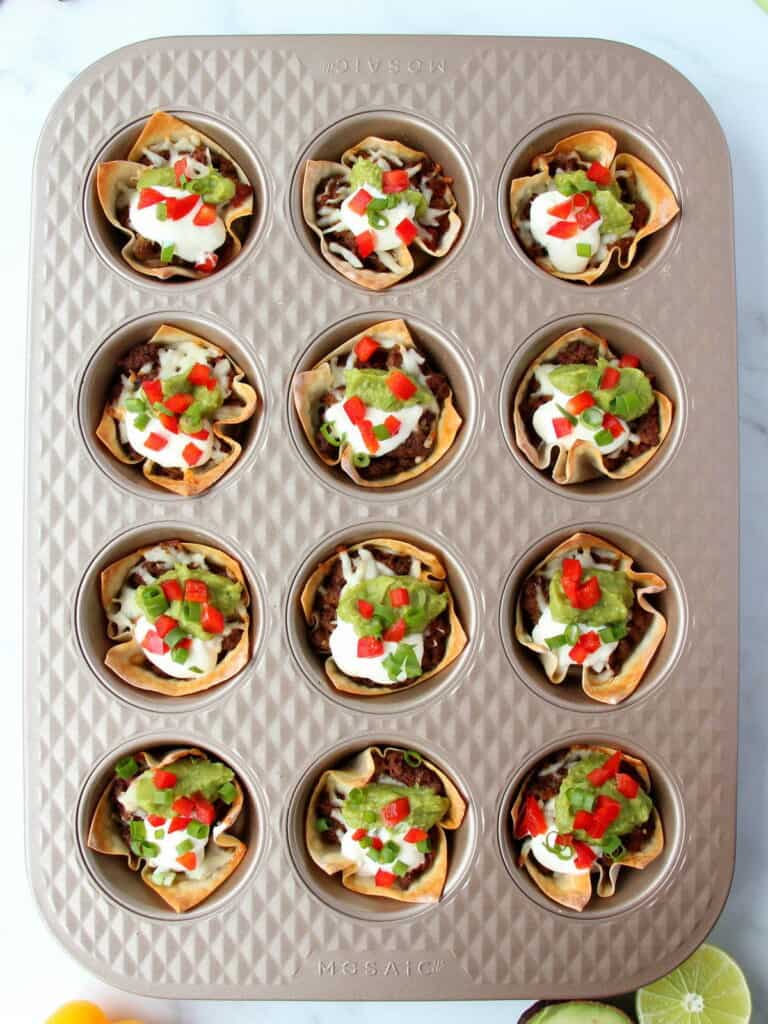 beef taco cups topped with sour cream and guacamole in Mosaic muffin pan
