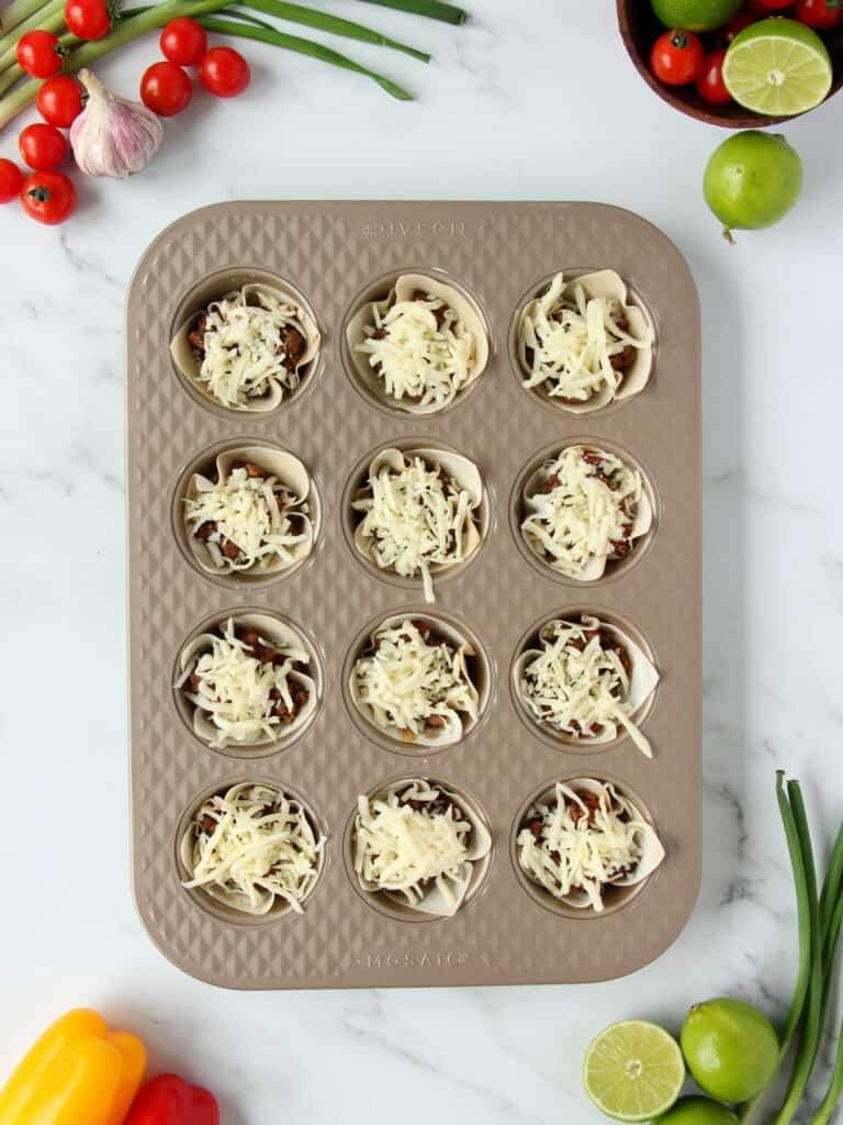 topping the taco cups with cheese