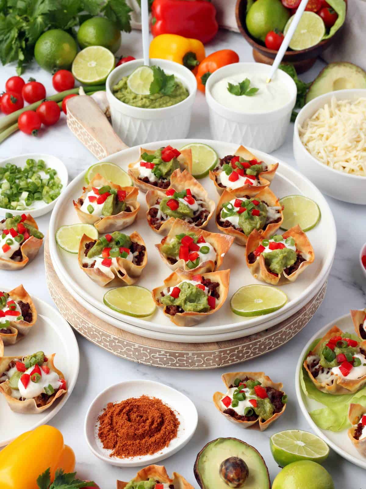 white plate full of mini taco cups, surrounded by all the ingredients used in the recipe