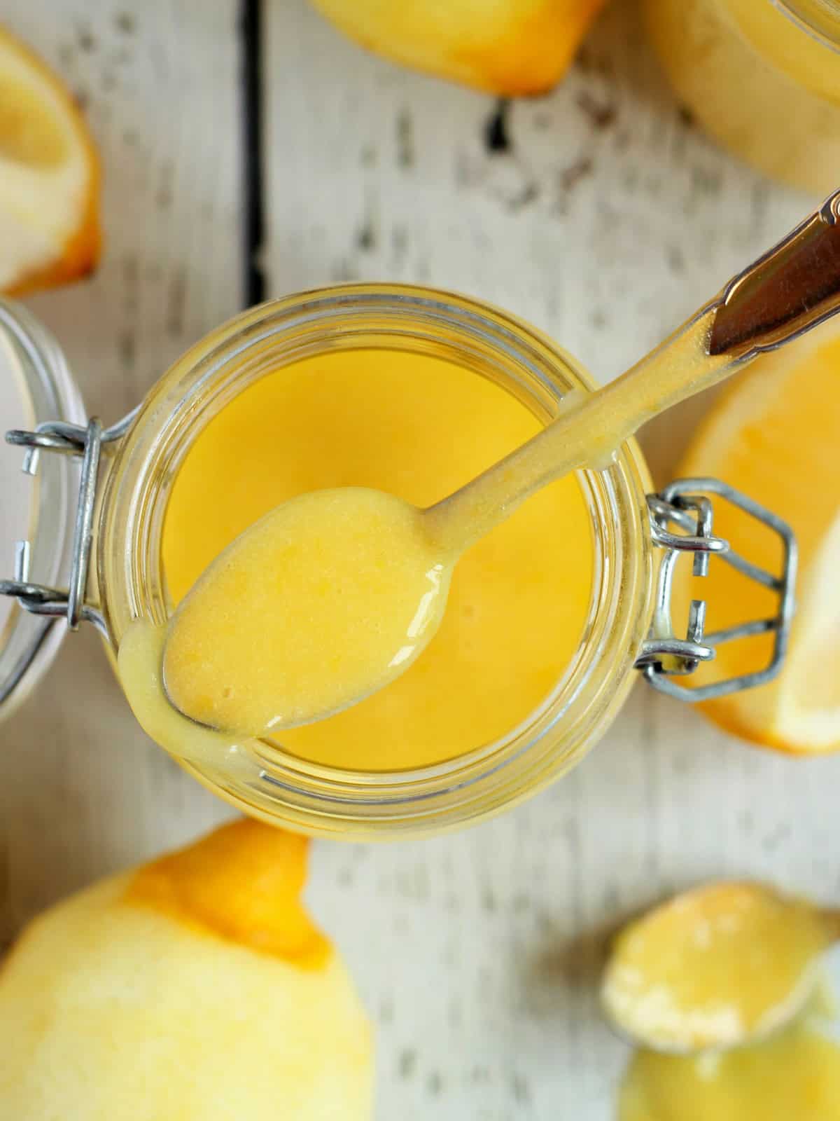 close up of lemon spread in mason jar with spoon inside.